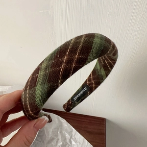 Detail of green and brown plaid fabric headband with handmade label and quilted texture