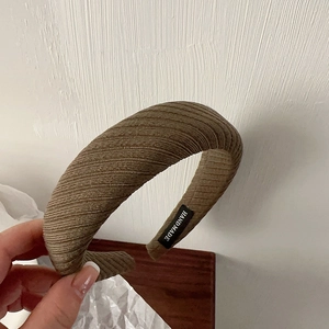 Macro detail of brown ribbed fabric headband showing handmade label and texture