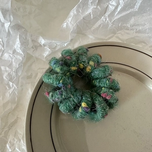 Détail d'un chouchou en peluche vert foncé avec points colorés sur une assiette en céramique