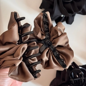 Detail of a large satin bow hair claw clip with layered pleats and vintage brown fabric