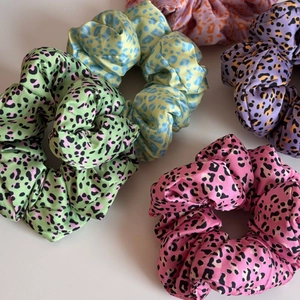 Gros plan de chouchous en satin à imprimé léopard coloré en vert, bleu, rose et orange