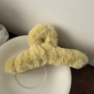 Detailaufnahme der weichen Plüschtextur einer großen hellgelben Kunstfell-Haarklammer