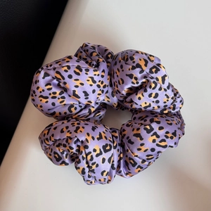 Détail d'un chouchou en satin violet à imprimé léopard avec un design élastique plissé