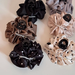 Flat lay of multiple satin hair claw clips with pearls and polka dot patterns