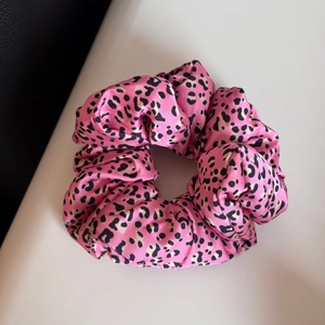 Détail d'un chouchou en satin imprimé léopard rose avec texture de tissu froissé