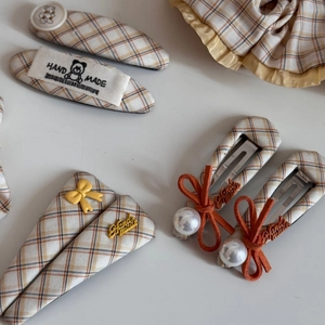 Detailed shot of yellow plaid fabric hair ties and clips with pearl and bow accents