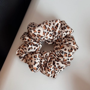 Gros plan détaillé du chouchou en satin à imprimé léopard avec une texture lisse et brillante