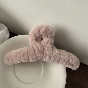 Nahaufnahme einer rosa Plüsch-Haarklammer mit weichem Kunstfell auf einem weißen Teller