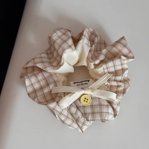 Detail of yellow checkered fabric hair scrunchie with ribbon bow and handmade label