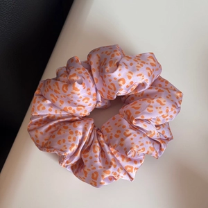Détail d'un chouchou en satin à motif léopard en violet clair et orange éclatant