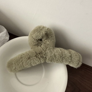 Detailaufnahme einer olivgrünen Plüsch-Haarklammer in einer weißen Keramikschale