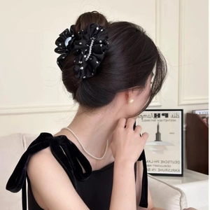 Detail of elegant black polka dot satin hair claw with white pearl accents on model