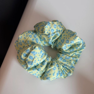 Détail du chouchou en satin à imprimé léopard avec taches bleu clair et texture lisse