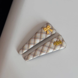 Detailed macro view of yellow plaid fabric hair clips with handmade lettering and bow decor