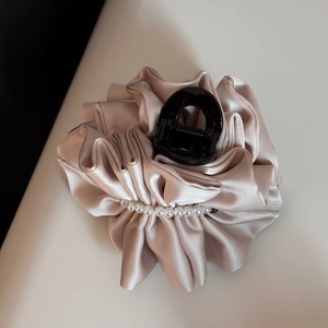 Detailed view of champagne pleated fabric hair claw clip with white pearls decoration