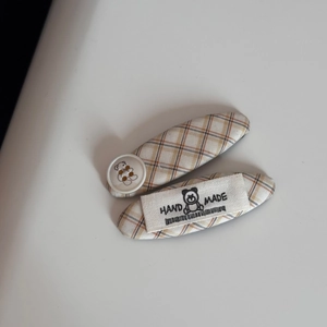 Detail of yellow plaid fabric hair clips with cute bear button and handmade woven label
