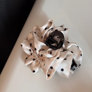 Detailed view of polka dot bow hair claw with elegant pearl accents and satin fabric