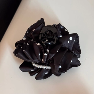 Close-up of black polka dot satin fabric hair claw clip with elegant white pearl accents