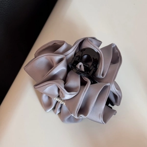 Detail view of grey satin fabric hair claw with elegant white pearls and pleated design