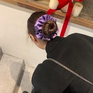 Elegant purple satin scrunchie made of silky fabric shown on a model hair bun