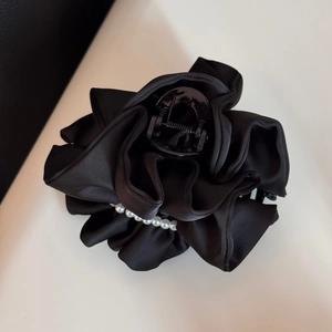 Detail of black satin fabric flower hair claw with white faux pearl line decoration