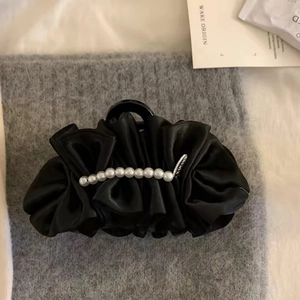 Detailed view of large black pleated fabric hair claw clip with white pearl embellishments