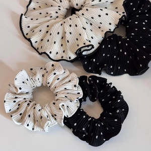 Detailed macro view of pleated polka dot scrunchies in black and white satin fabric