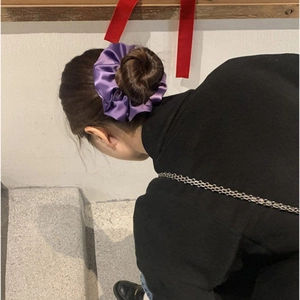 Detail of a purple satin oversized scrunchie styled on a classic french bun hairstyle