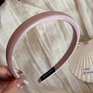 Détail du serre-tête en satin rose clair avec étiquette tissée à la main noire
