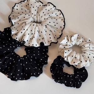 Detailed view of four black and white polka dot scrunchies with pleated organza texture
