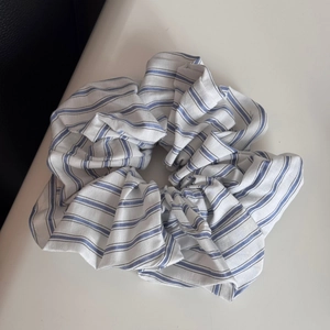 Detailed shot of blue and white striped fabric scrunchie with soft cotton pleated texture