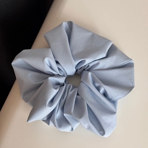 Detail of light blue plaid fabric scrunchie with soft pleats and fine stitching