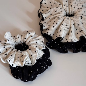 Detailed view of oversized pleated polka dot scrunchies in premium black and white fabric.
