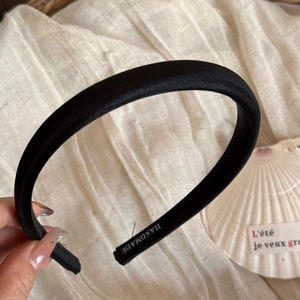 Détail d'un serre-tête en velours noir avec étiquette faite main sur tissu