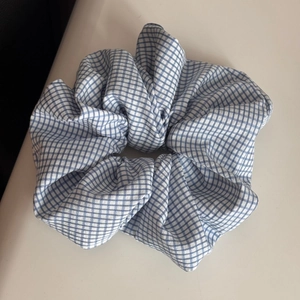 Close-up of a large blue and white gingham fabric scrunchie with soft ruffled texture