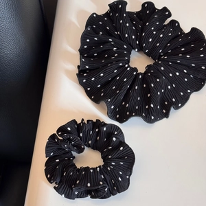 Detail of two black polka dot pleated scrunchies in different sizes for hair styling