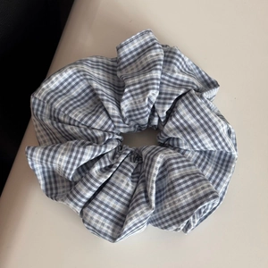 Detail of blue and white plaid scrunchie with visible white decorative stitching
