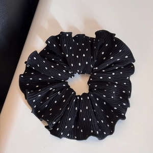 Detail of a black and white polka dot scrunchie with soft ruffled fabric texture