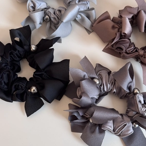 Détail des chouchous en satin avec nœuds et perles dans les tons gris et noirs