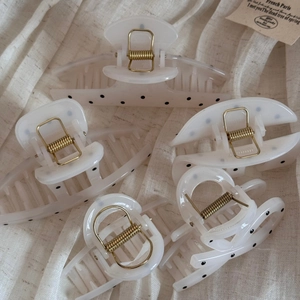 Flat lay of cream polka dot hair claws in various sizes on textured linen fabric