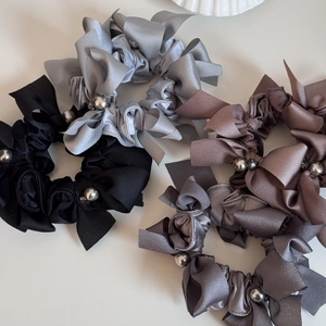 Détails de chouchous en satin avec nœuds et perles dans les tons gris et roses