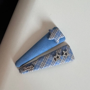 Detail view of blue plaid star fabric hair clips with small rhinestones and metal script