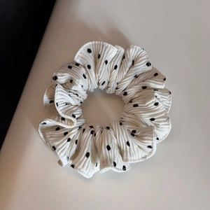 Detailed view of white polka dot scrunchie with pleated texture and soft fabric