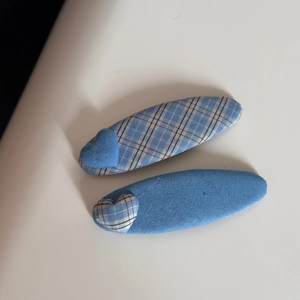 Close-up of blue plaid fabric hair clips featuring contrasting heart shaped decorations