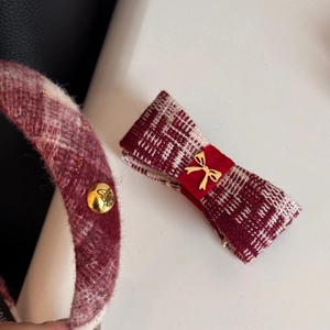 Detailed macro view of red plaid tweed headband and bow clip with golden insect relief buckle