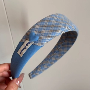 Close-up of blue plaid fabric headband with heart decoration and Late Premium label