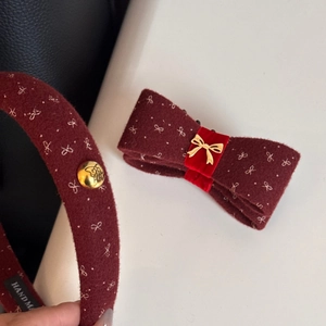 Detail of burgundy bow banana clip and headband with gold embroidery and metal button