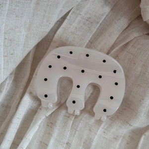 Detail view of wavy polka dot hair claw clip on soft beige textured background