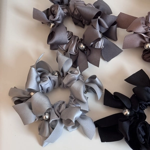 Détail des chouchous à nœud en satin élégants avec perles grises et texture soie