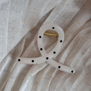 Detail of twisted ribbon hair claw clip with black polka dots on cream acetate material